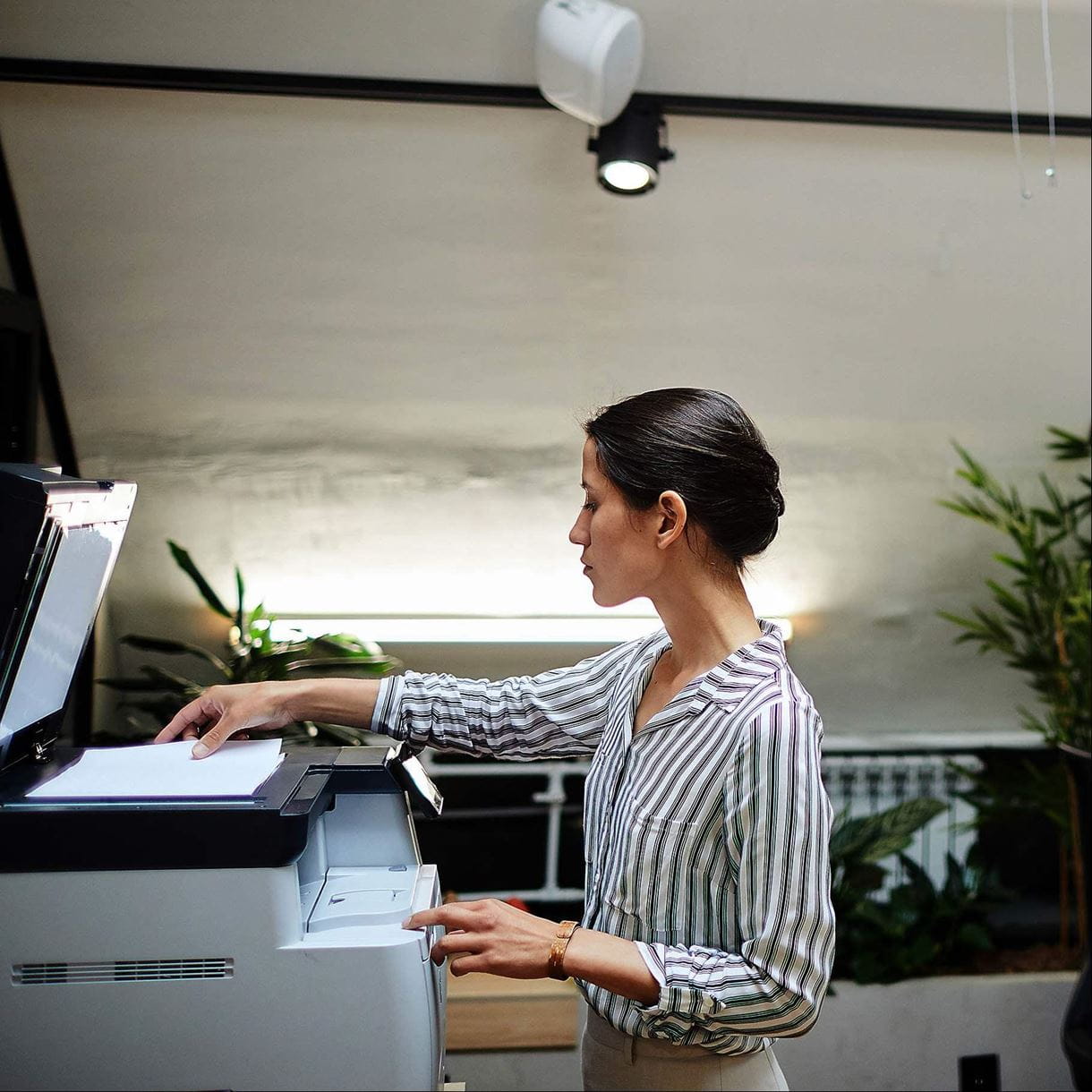 Side view portrait of young businesswoman scanning documents while working in office, copy space