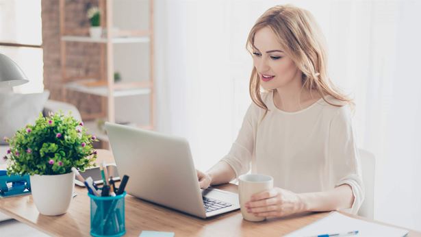 Happy pretty cute woman working with computer drinking coffee